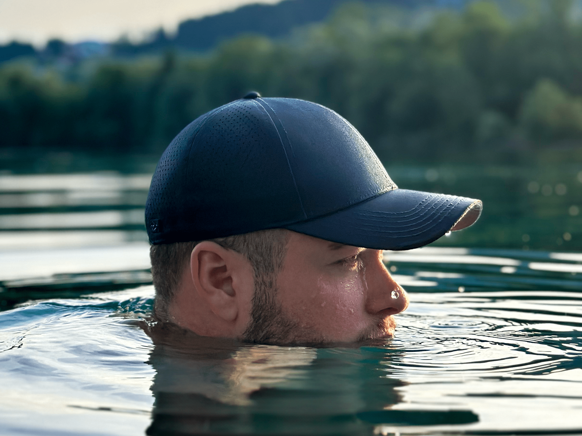 Mann mit blauer apol Cap schwimmt und nur hälfte des Kopfes schaut aus Wasser